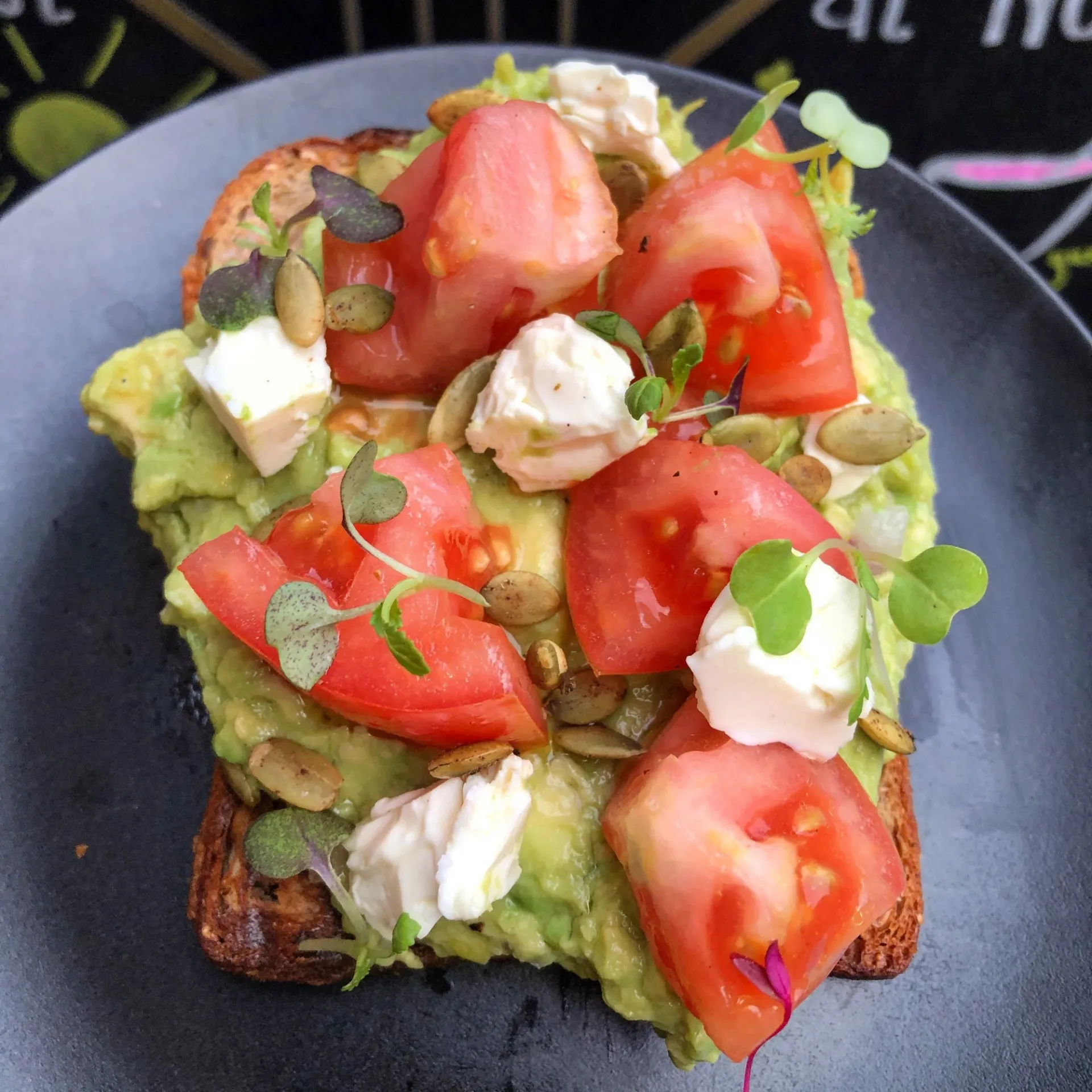 Avocado toast with tomatoes, feta cheese, and pepitas