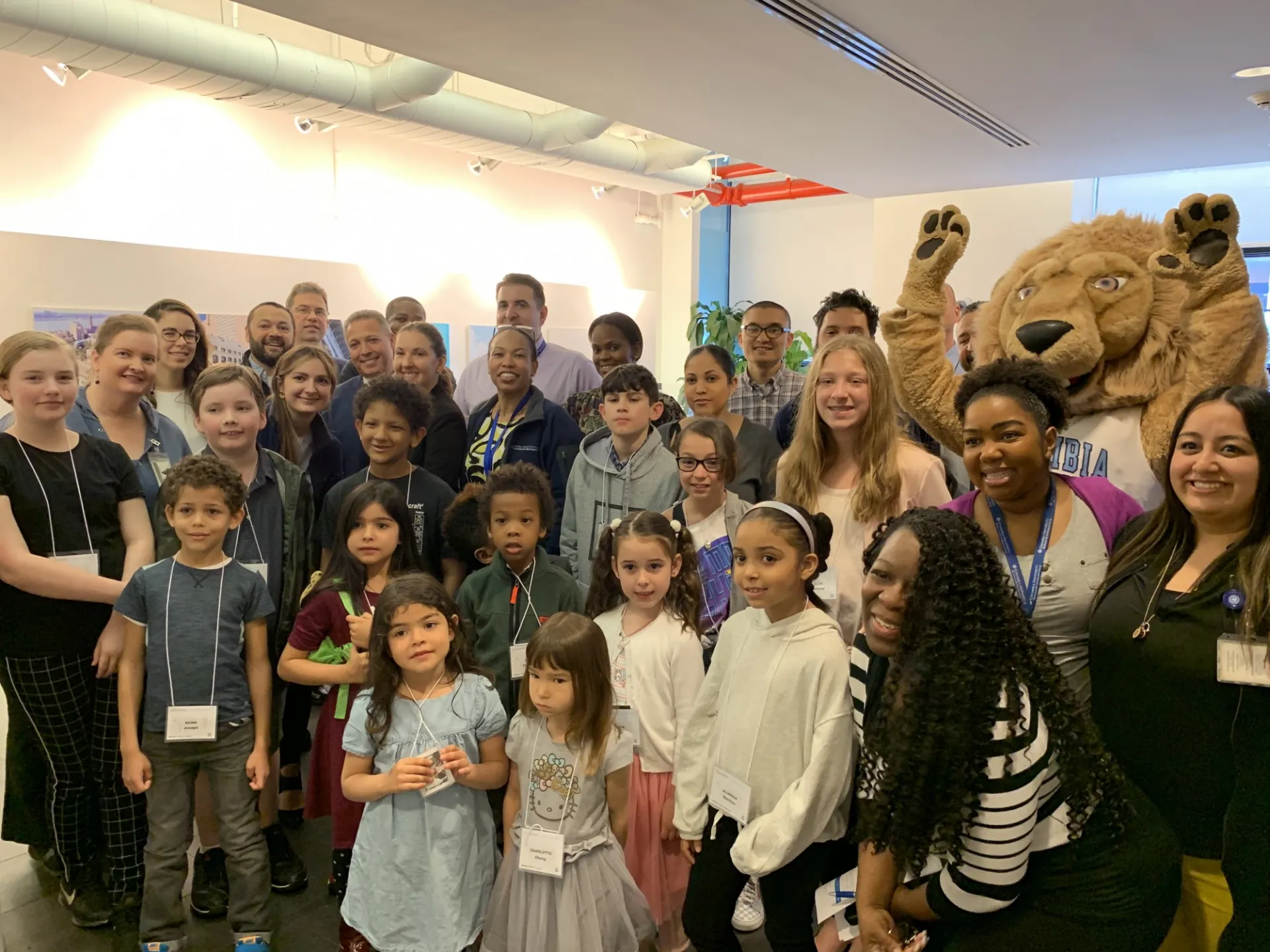 Facilities and Operations employees and their children pose with Roaree the Lion