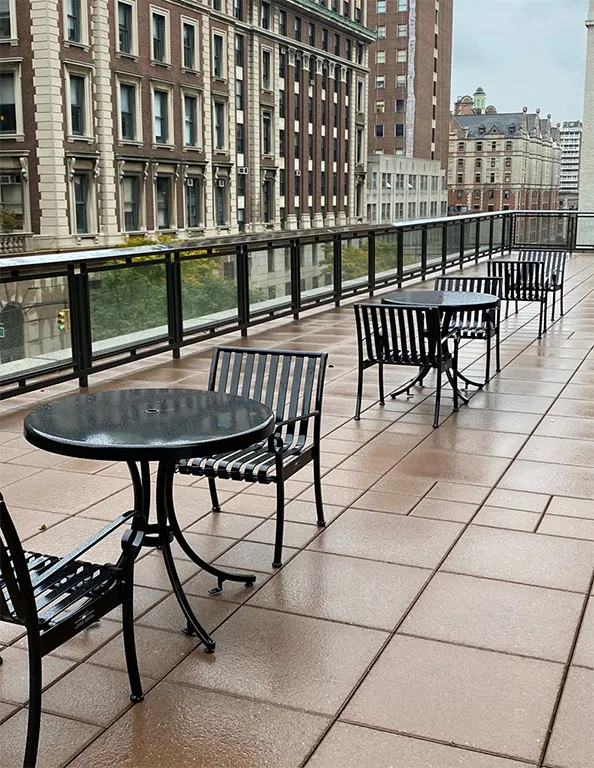 Black cafe tables and chairs line the International Affairs Building terrace. 