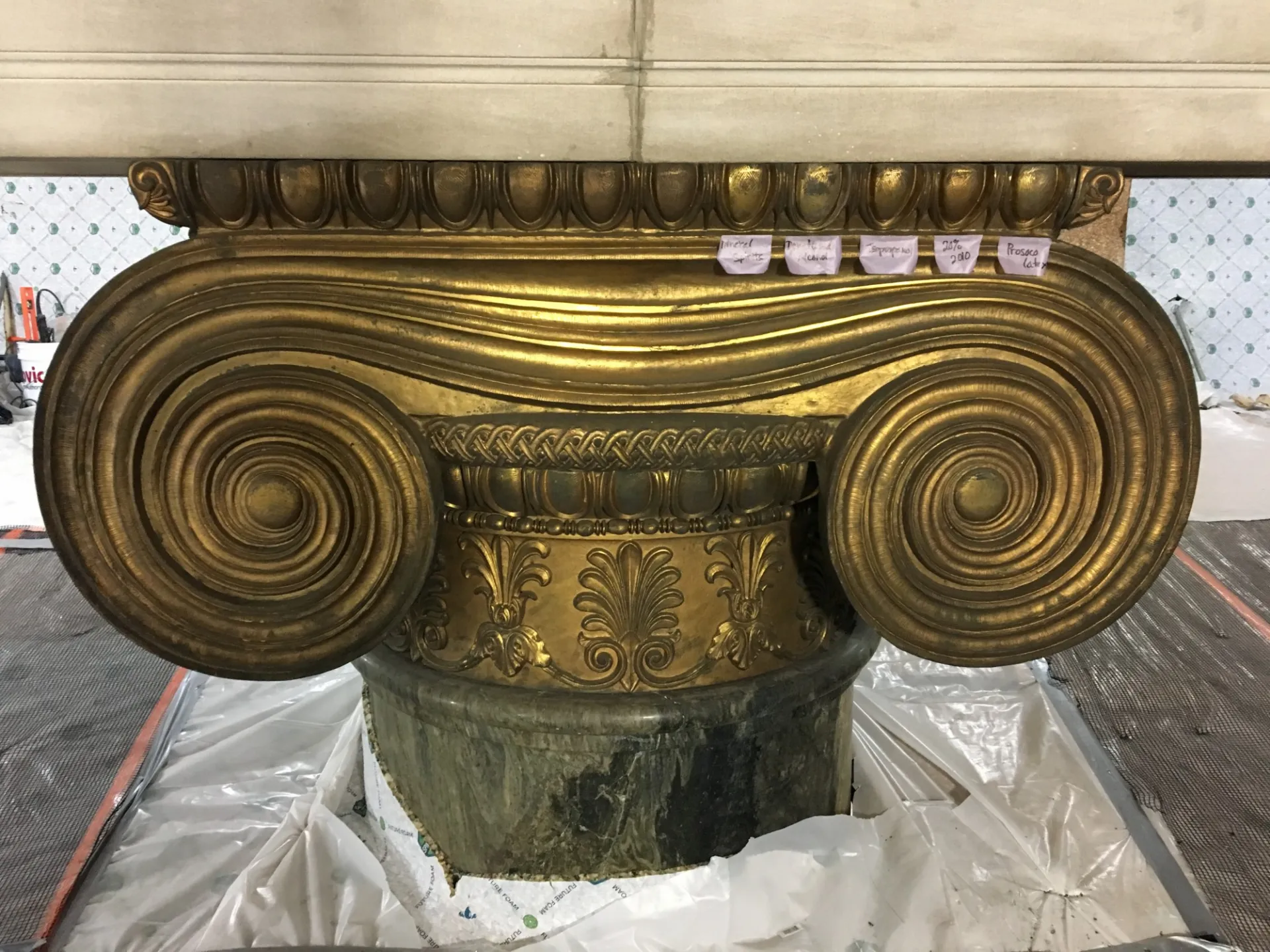 The historic preservation contractor tests multiple cleaning agents at the gilded bronze column capital to determine which one will most effectively restore the intended finish.
