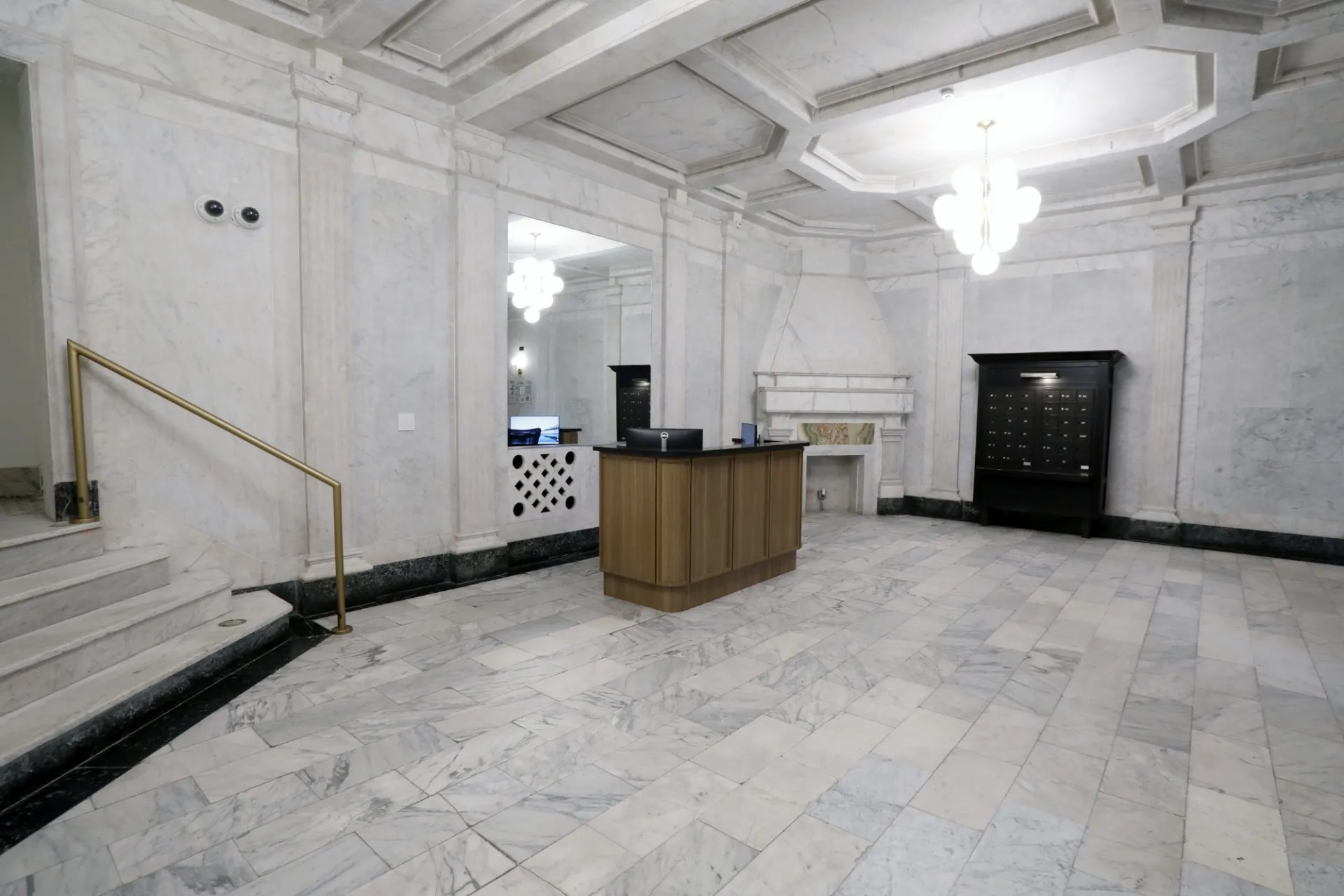 A white marble lobby with a decorative fireplace and wood accent desk.