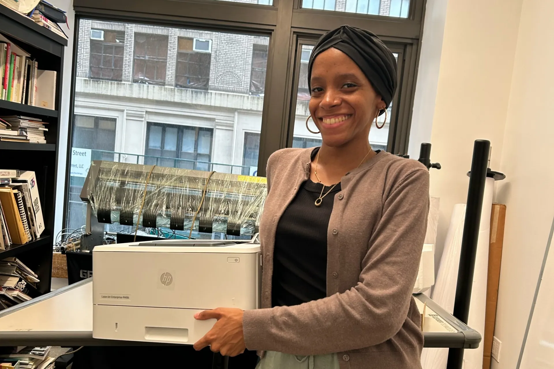 A person holds a new printer in their office.