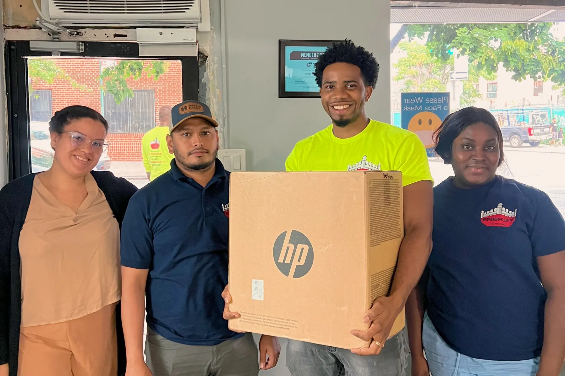 A group of people stand next to a HP printer box.