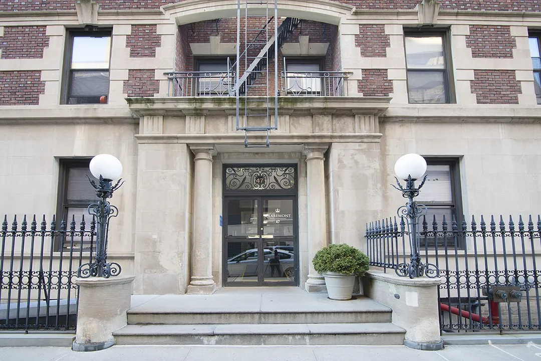 The entrance to 47 Claremont, with a brick facade beginning on the second floor, two colums surrounding the main entrance, and large round lights at the end of the entrance steps.