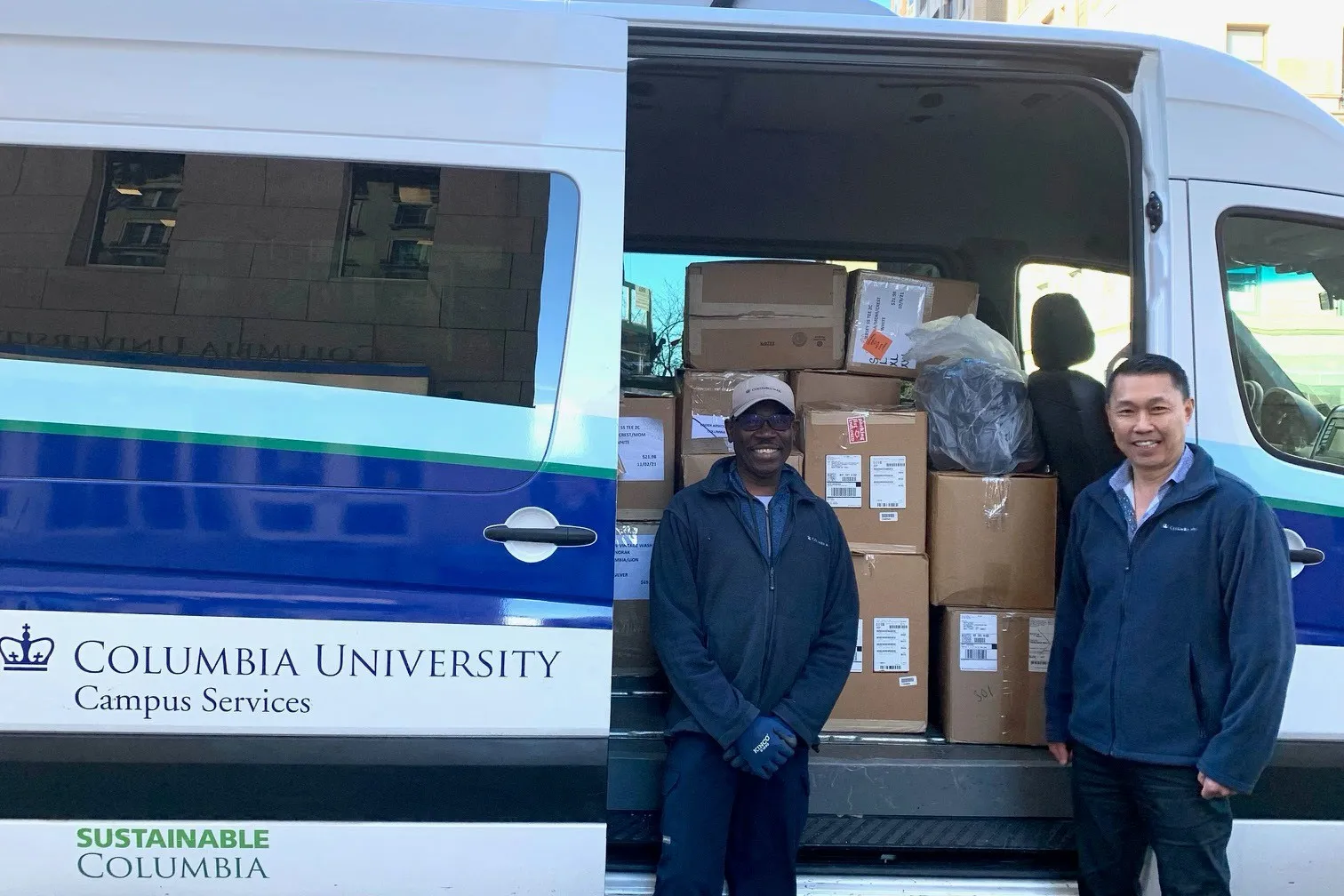 Facilities and Operations employees stand by a Campus Services van that is packed with donated goods.