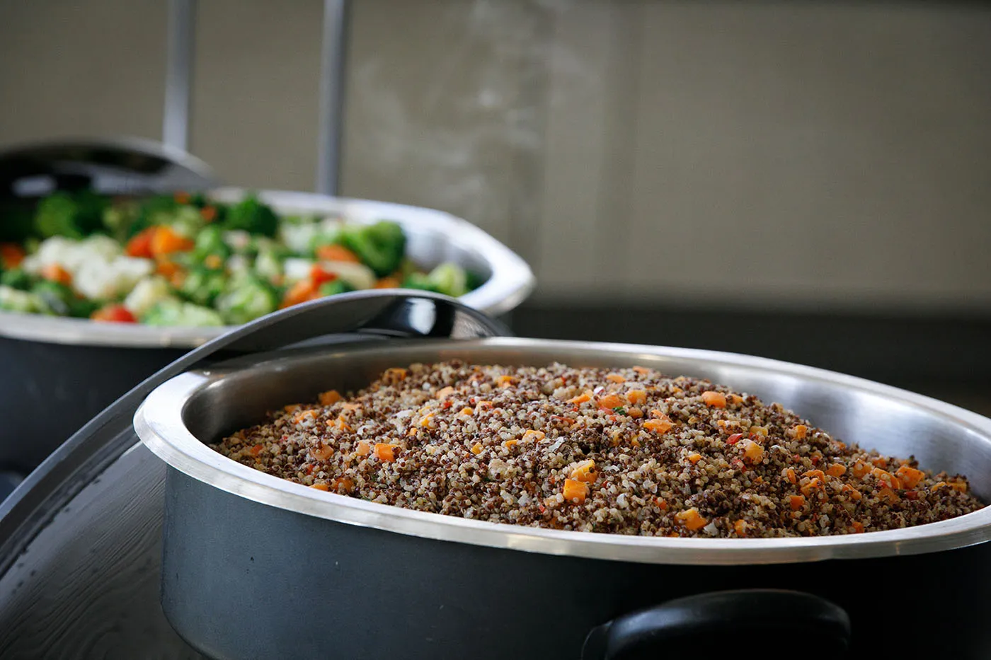 Quinoa pilaf and vegetable medley in black serving dishes.