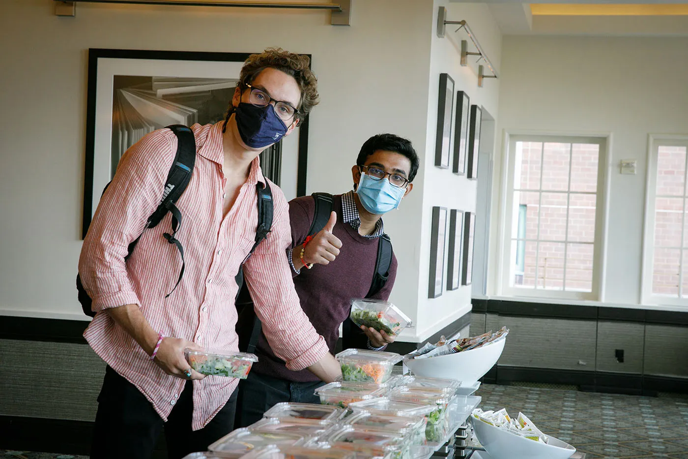 Two students standing at the salad bar grabbing pre-packaged salad.