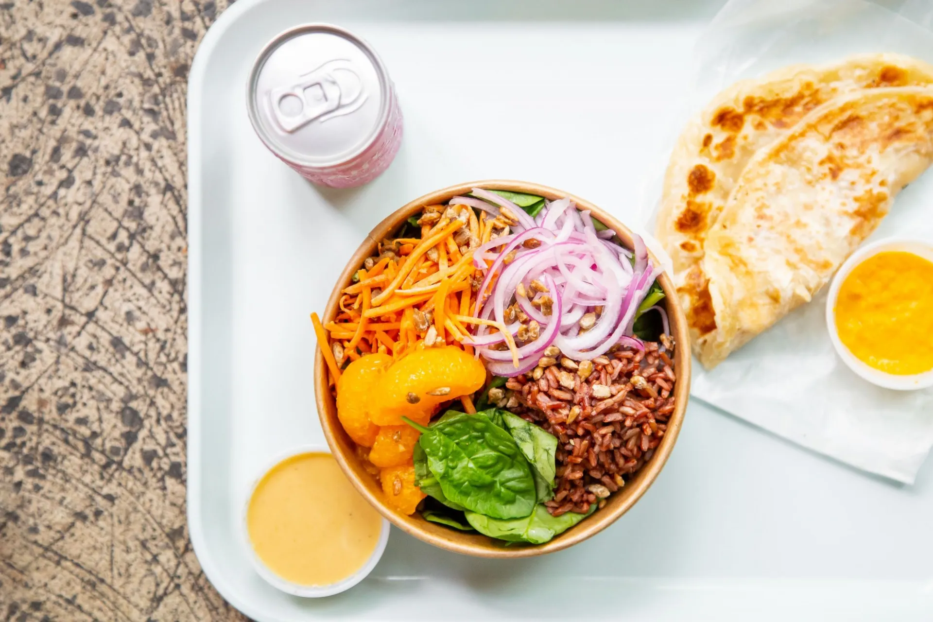 A white tray with a rice bowl from FIELDTRIP, along with a side of flatbread and can of soda.