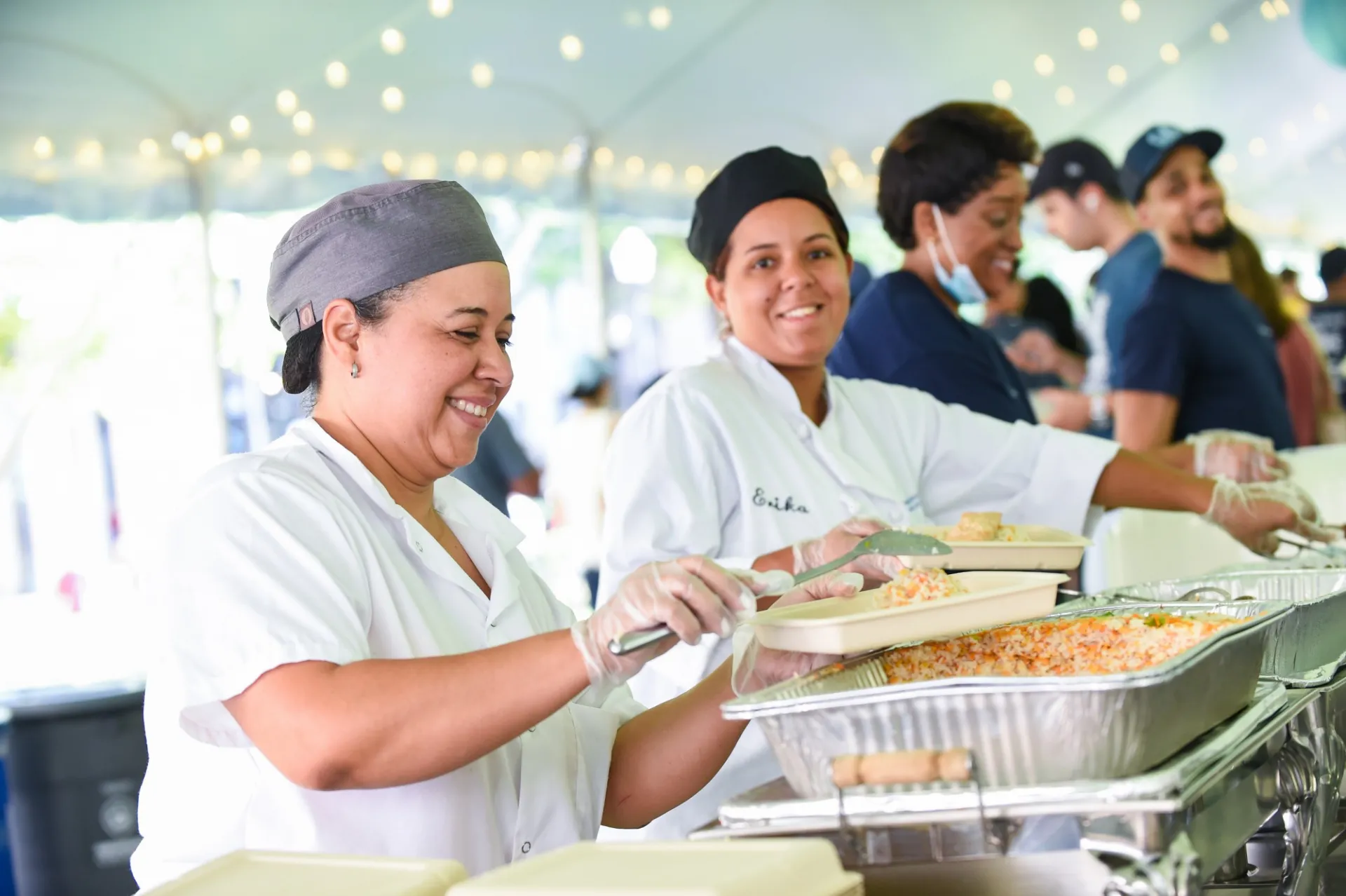 A group of Columbia dining employees fill to go plates with food from a catering station.