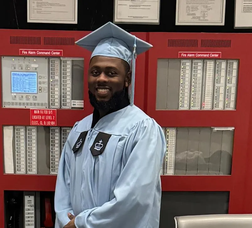 Dauda Musah poses for a photo in graduation regalia in the fire safety command station