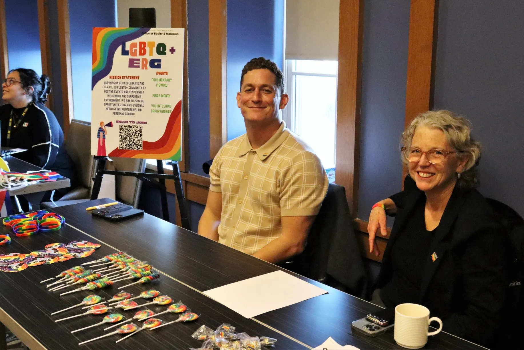 The chairs of the LGBTQ+ employee resource group posing for a photo at their ERG's table