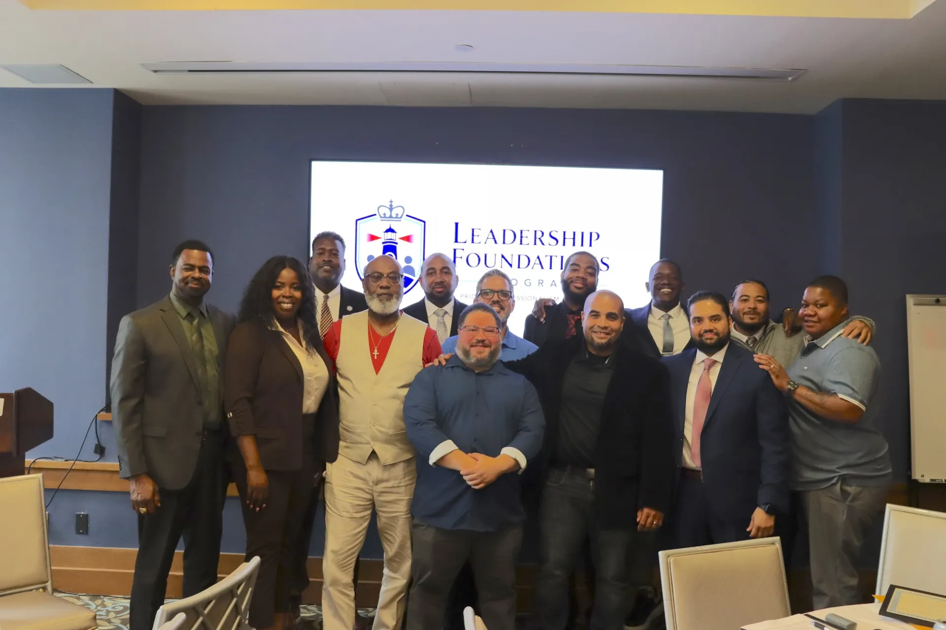 Group photo in front of powerpoint that says "Leadership Foundations Program"