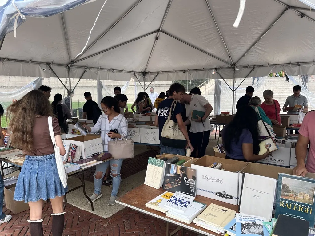 People perusing through used books under the tent at Clean + Go Green