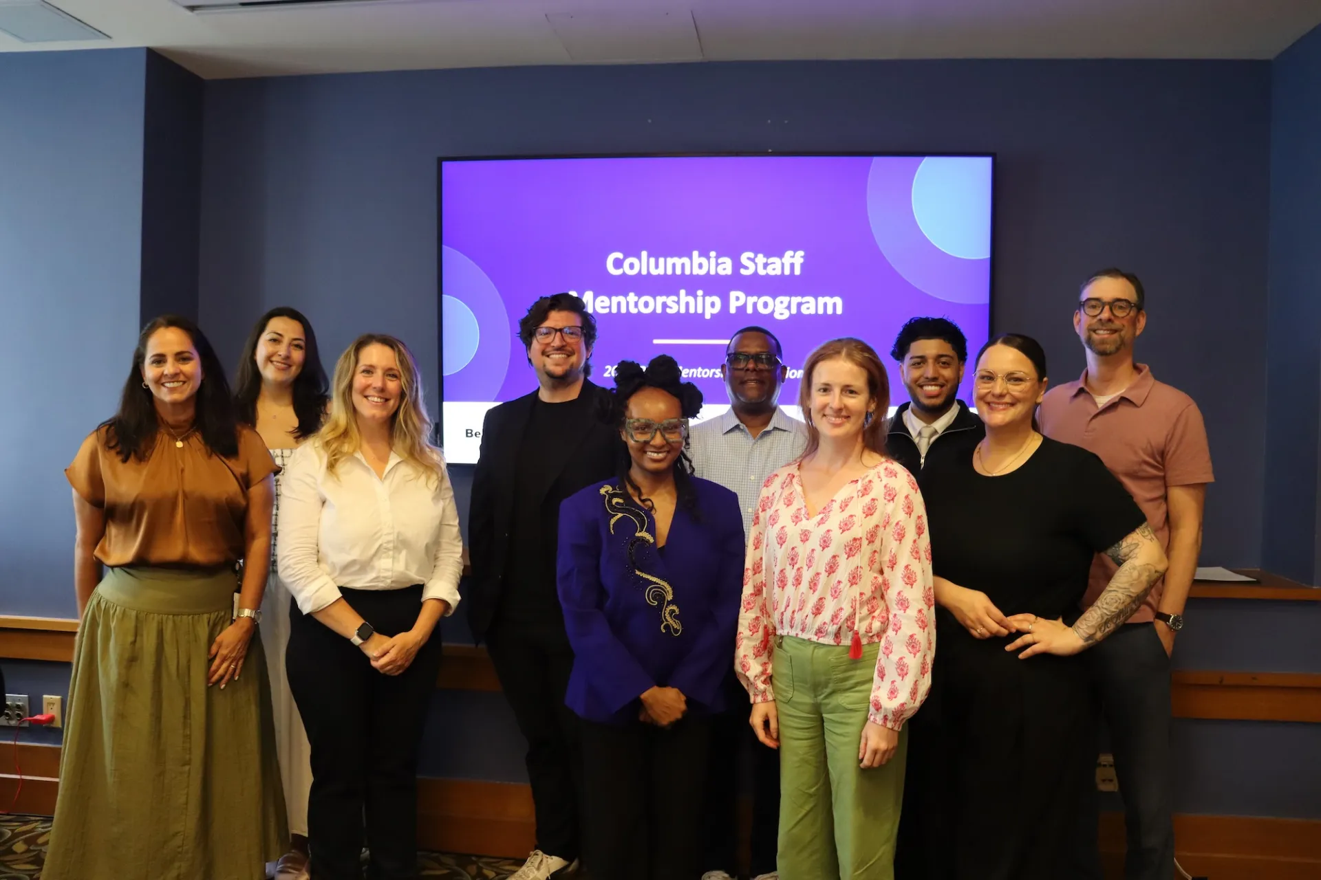 Group of people stand in front of screen that says Columbia Staff Mentorship Program