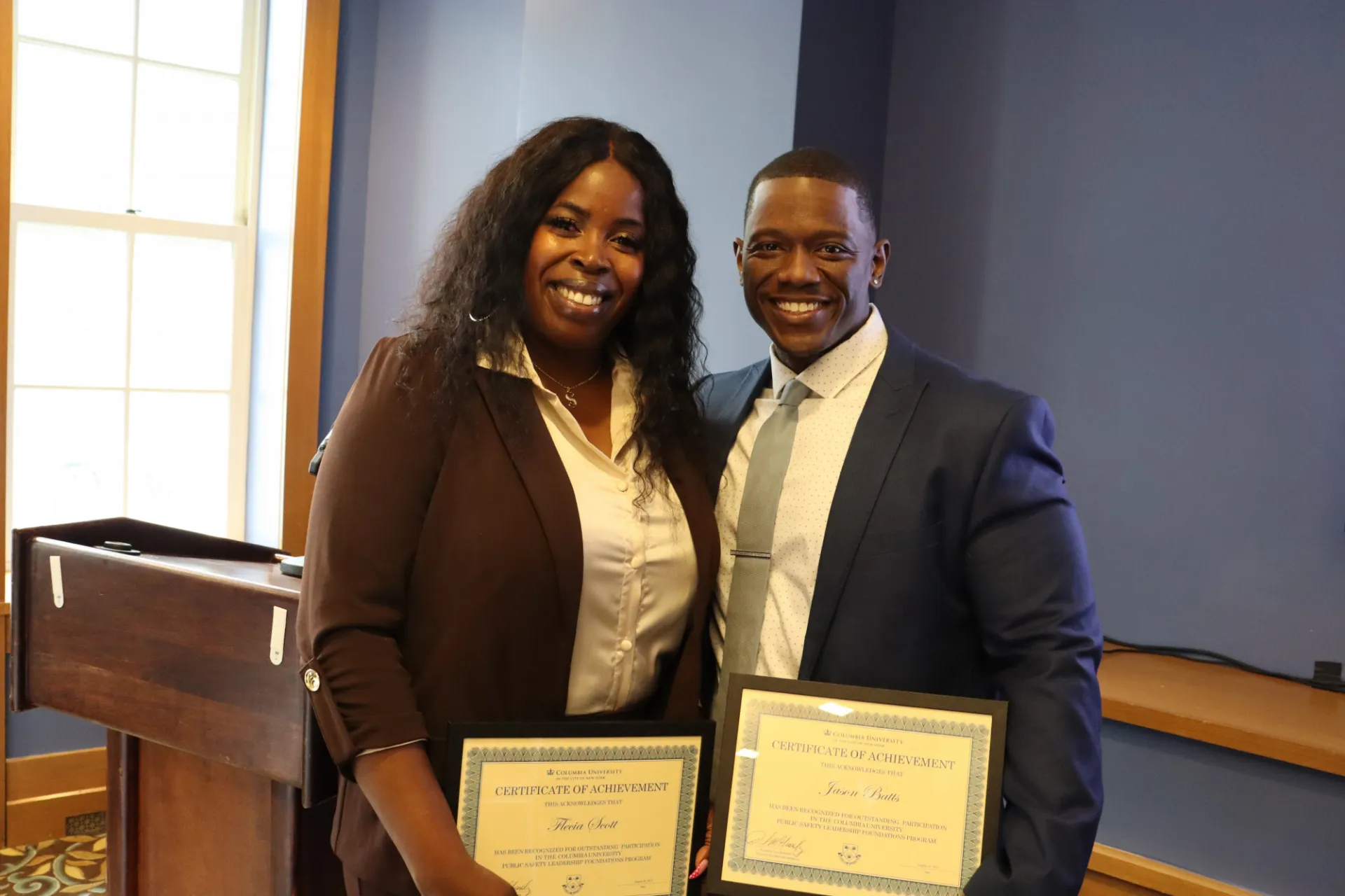 two people smiling and holding certificates 
