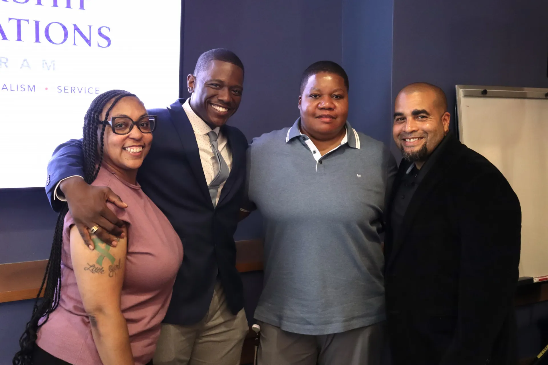 Four people stand together smiling