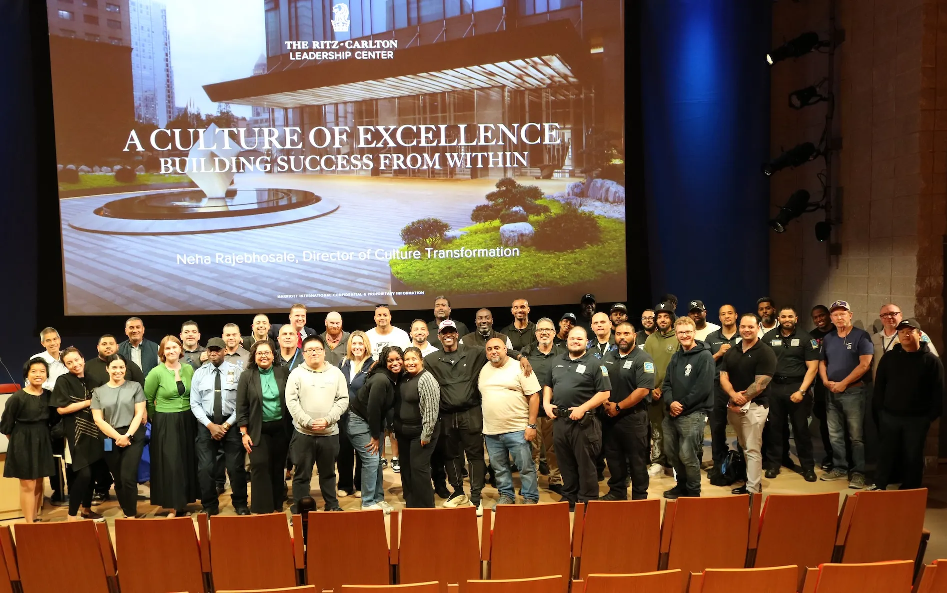 "Group in front of screen displaying 'The Ritz-Carlton Leadership Center' and 'A Culture of Excellence' with Neha Rajehunsale."