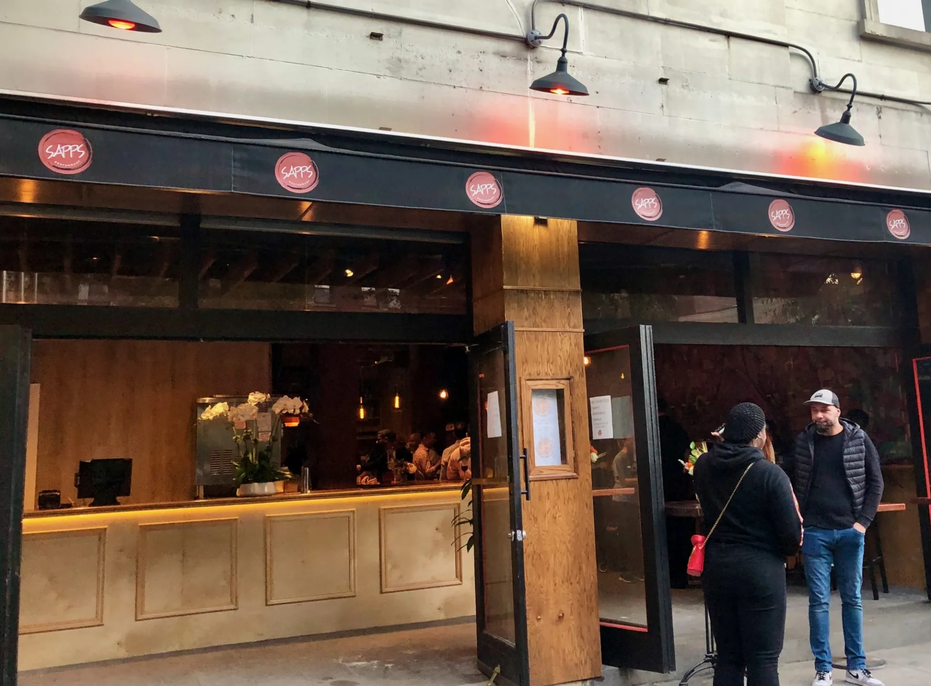 The storefront of Sapp's Restaurant, with a black awning over their main entrance with their red circle logos on it.