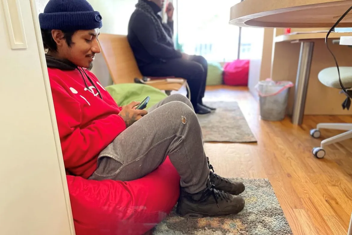 A person sitting on a red bean bag looking at their phone and smiling.