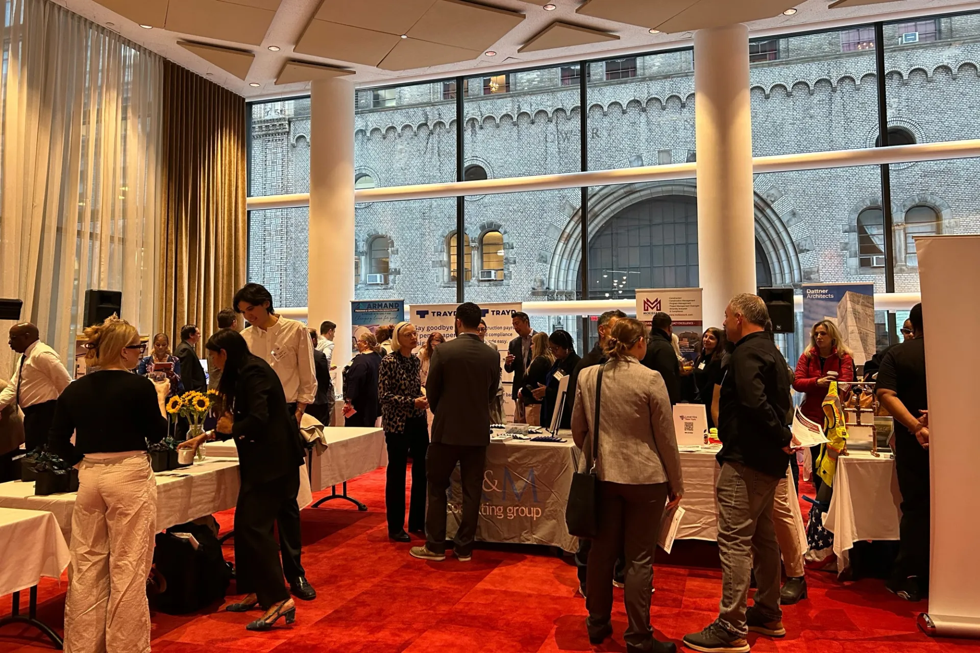 A group of people gather in a room to view different vendors displaying their businesses.