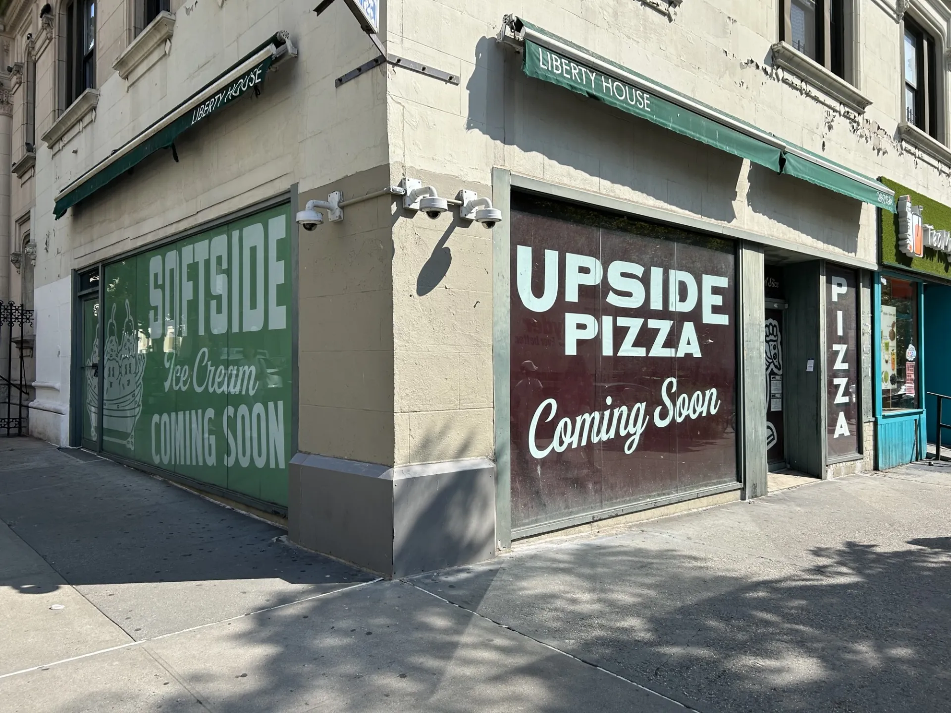 A storefront that has signage in the windows that says Upside Pizza and Softserve Ice Cream is coming soon.