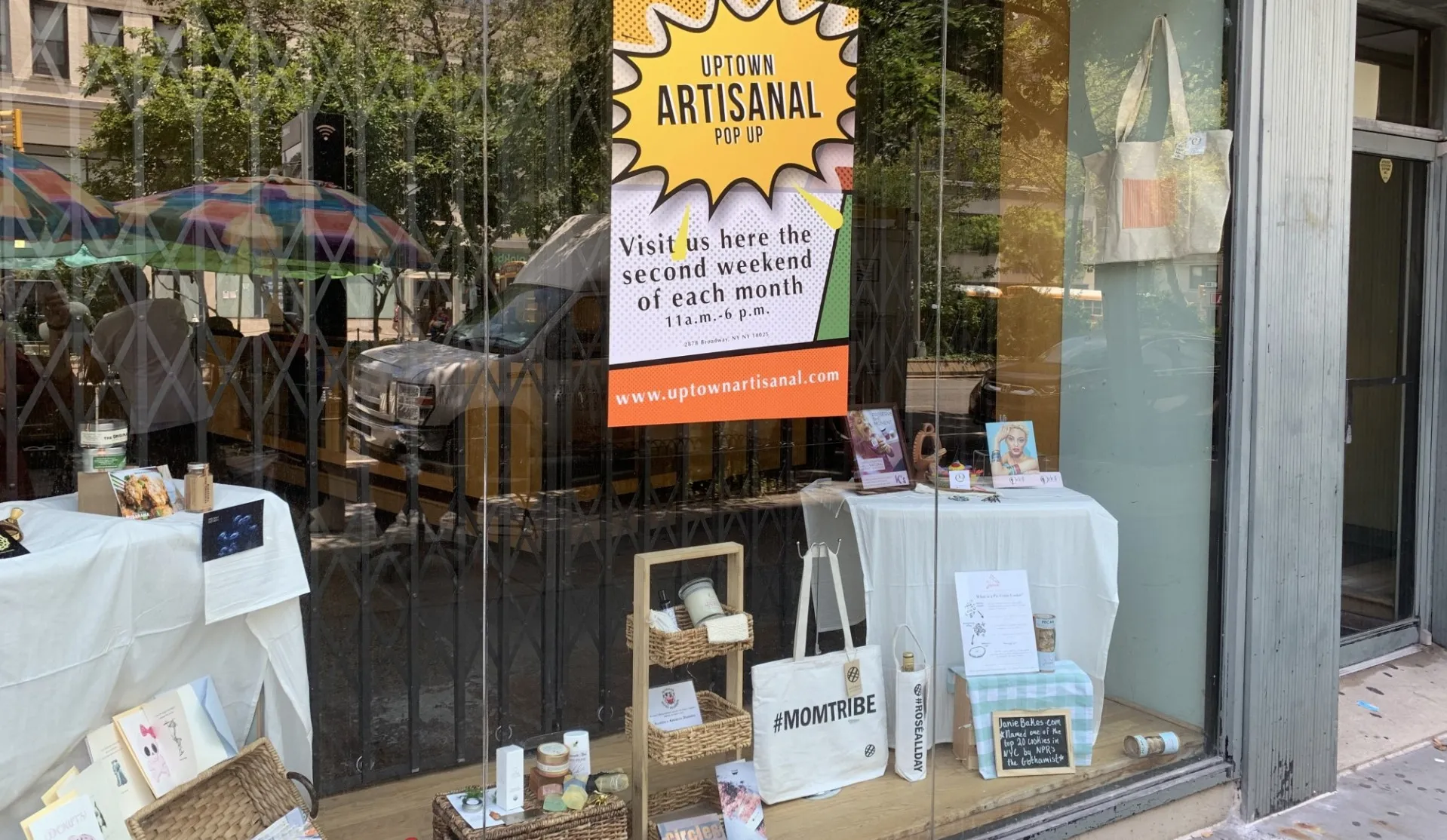 A storefront for the Uptown Artisanal pop-up market, which has a flyer and a sampling of items in the window.