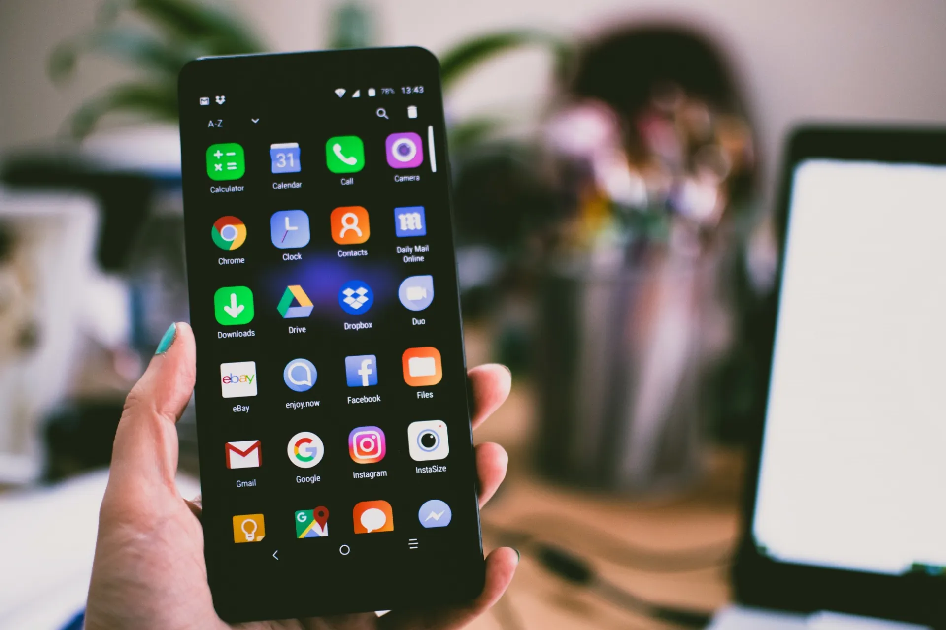 A person is holding an unlocked cell phone in front of the camera at their desk