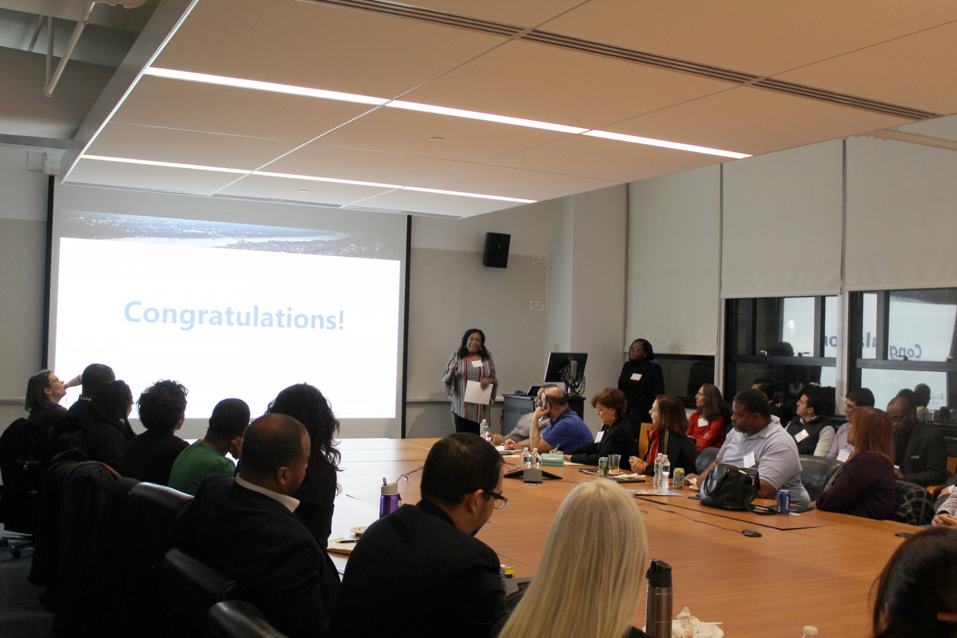 A group of people sit in a conference room as someone presents on the CU Grow Program