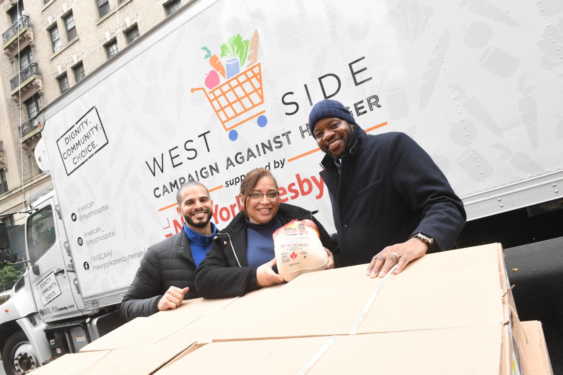Over 500 employees chose to support Columbia Community Service and donate their food gift to the West Side Campaign Against Hunger. three people posing in front of truck that says: West Side Campaign Against Hunger