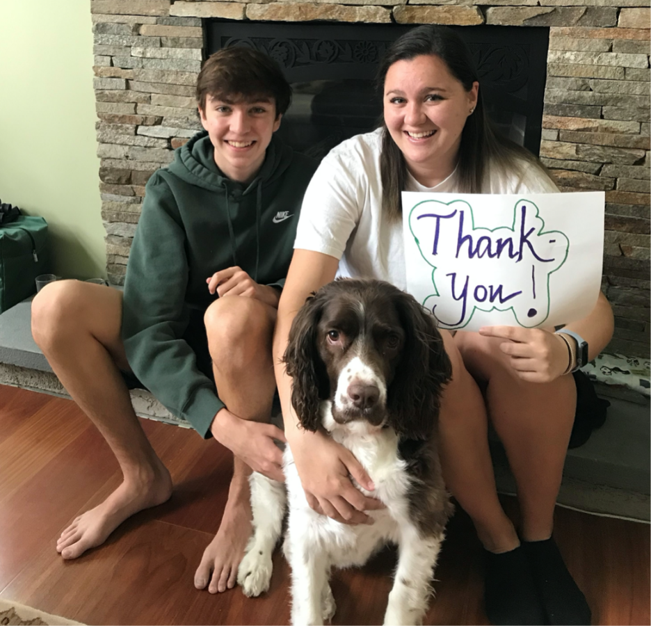 boy, woman and dog sit by fireplace with Thank You sign