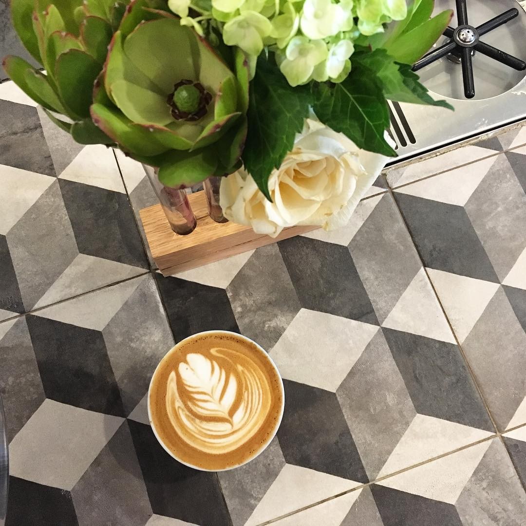 A latte next to a vase of flowers