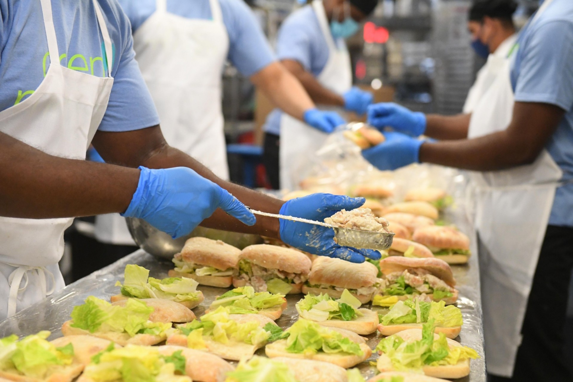 Dining staff member scoops chicken salad onto a sandwich in John Jay Dining Hall