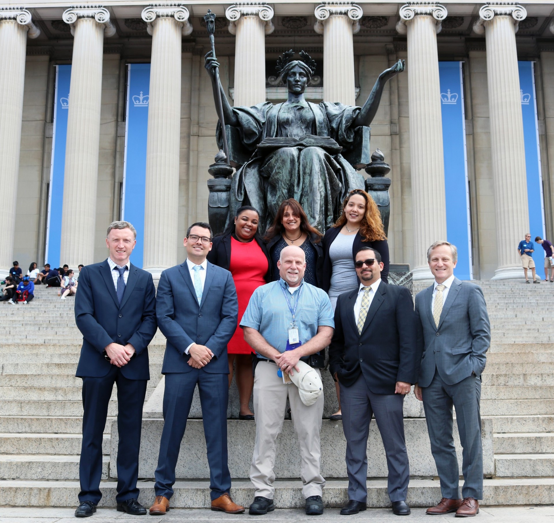 Back row, from left: Grace Urena, Lara Simone, Denise Abad; Front row, from left: Liam McMahon, Cyle Timmons, Bryan Violetto, Jose Morel, Executive Vice President for Facilities & Operations David Greenberg. A group of CUFO graduates in front of Alma Mater statue
