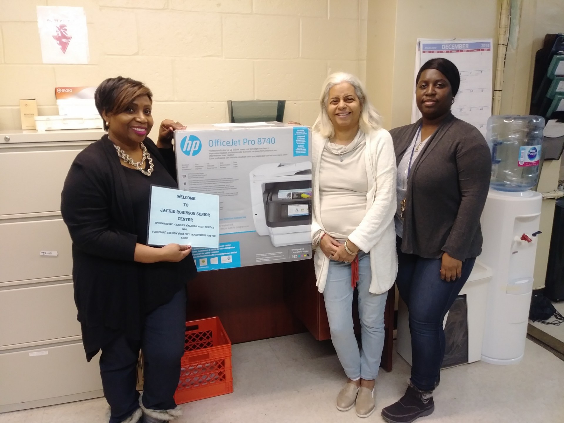 Three employees at the Grant Houses Jackie Robinson Senior Center receiving a new printer from Columbia University.