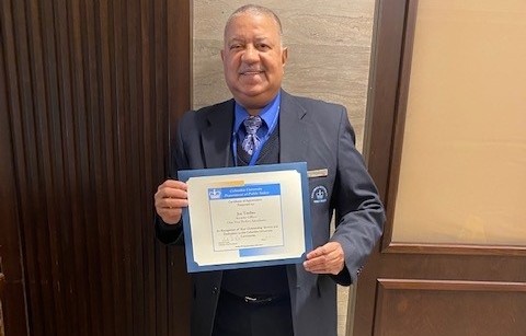 Security Officer Joe Toribio Celebrates 1 Year of Perfect Attendance man in a suit holding up perfect attendance certificate
