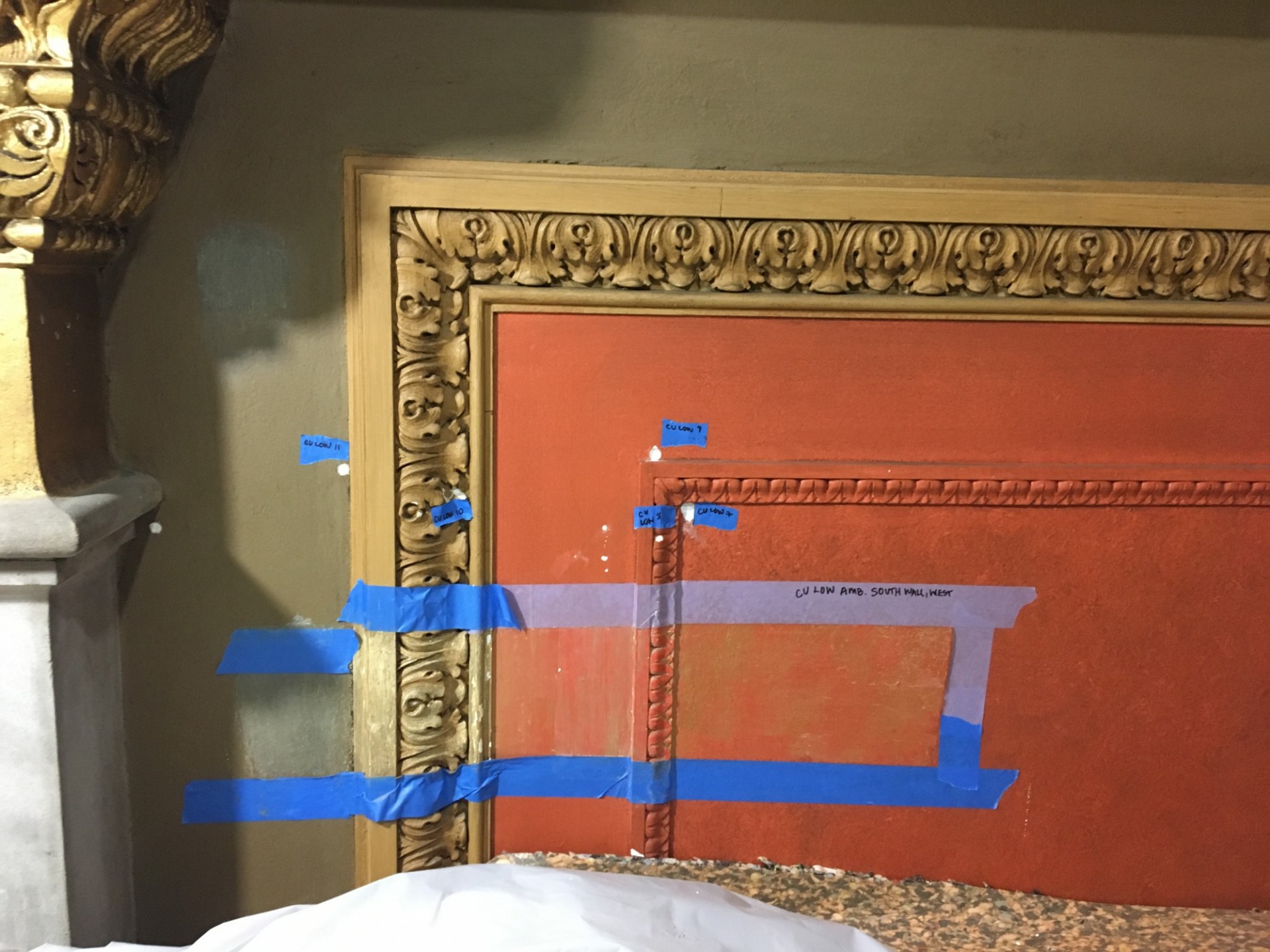 A red orange section of the wall being being investigated to determine the correct paint color.
