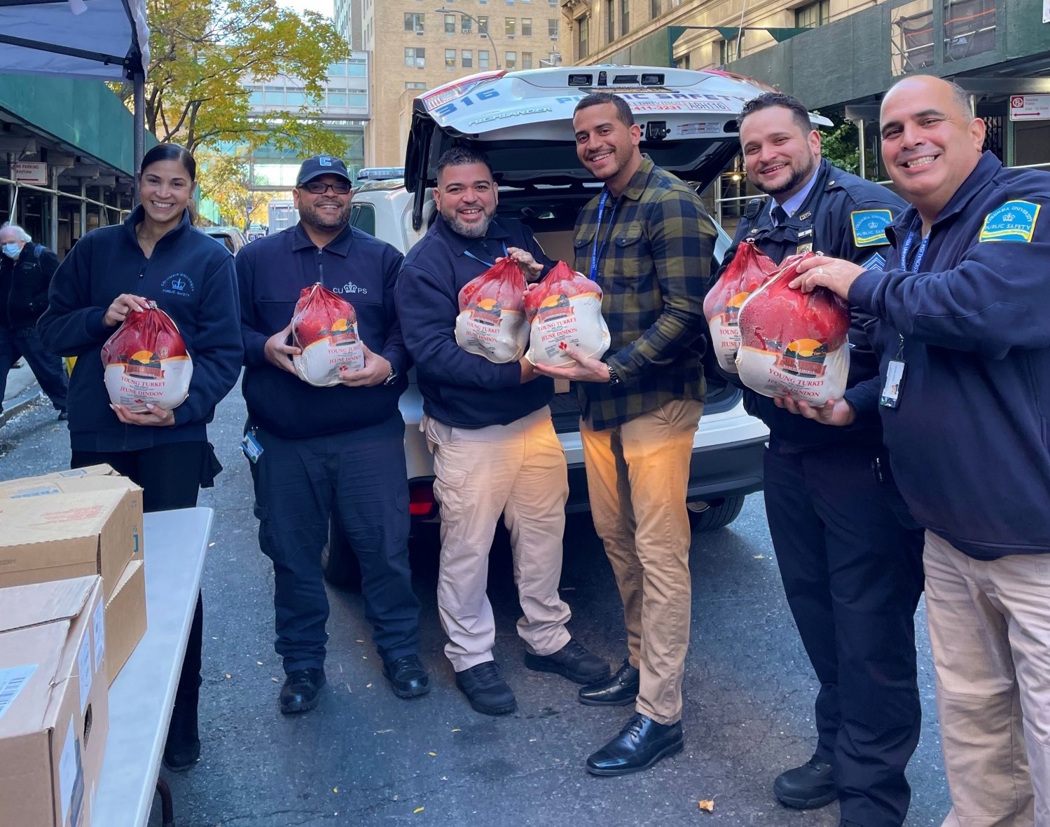 One woman and five men from Columbia Public Safety holding a turkey