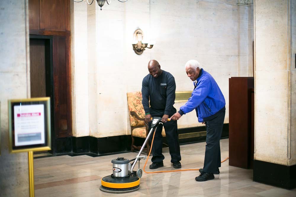 CUFO custodial workers polish the floors in the lobby of University Apartment Housing.