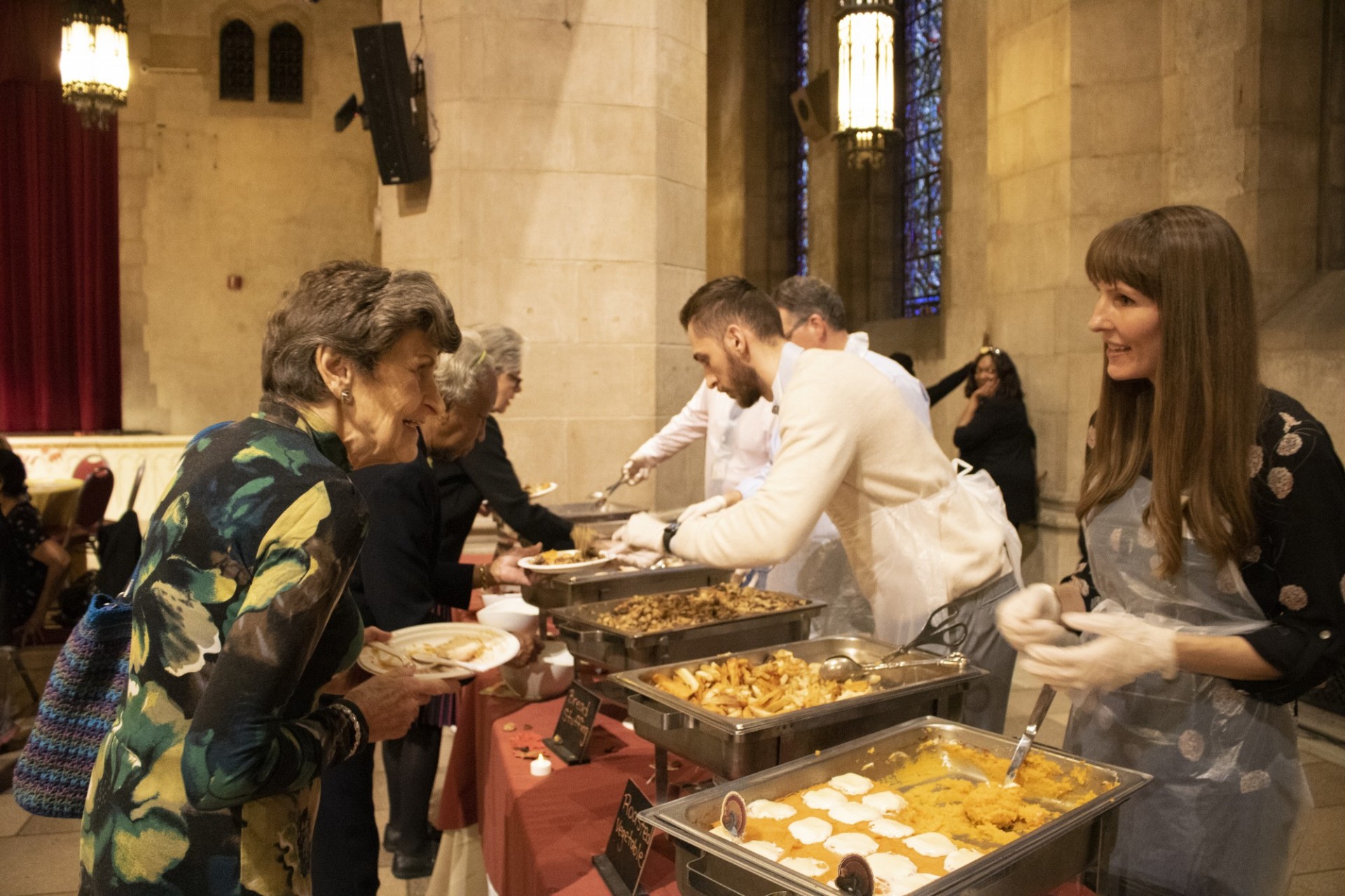 A senior citizen receives food from a Thanksgiving buffet from a volunteer