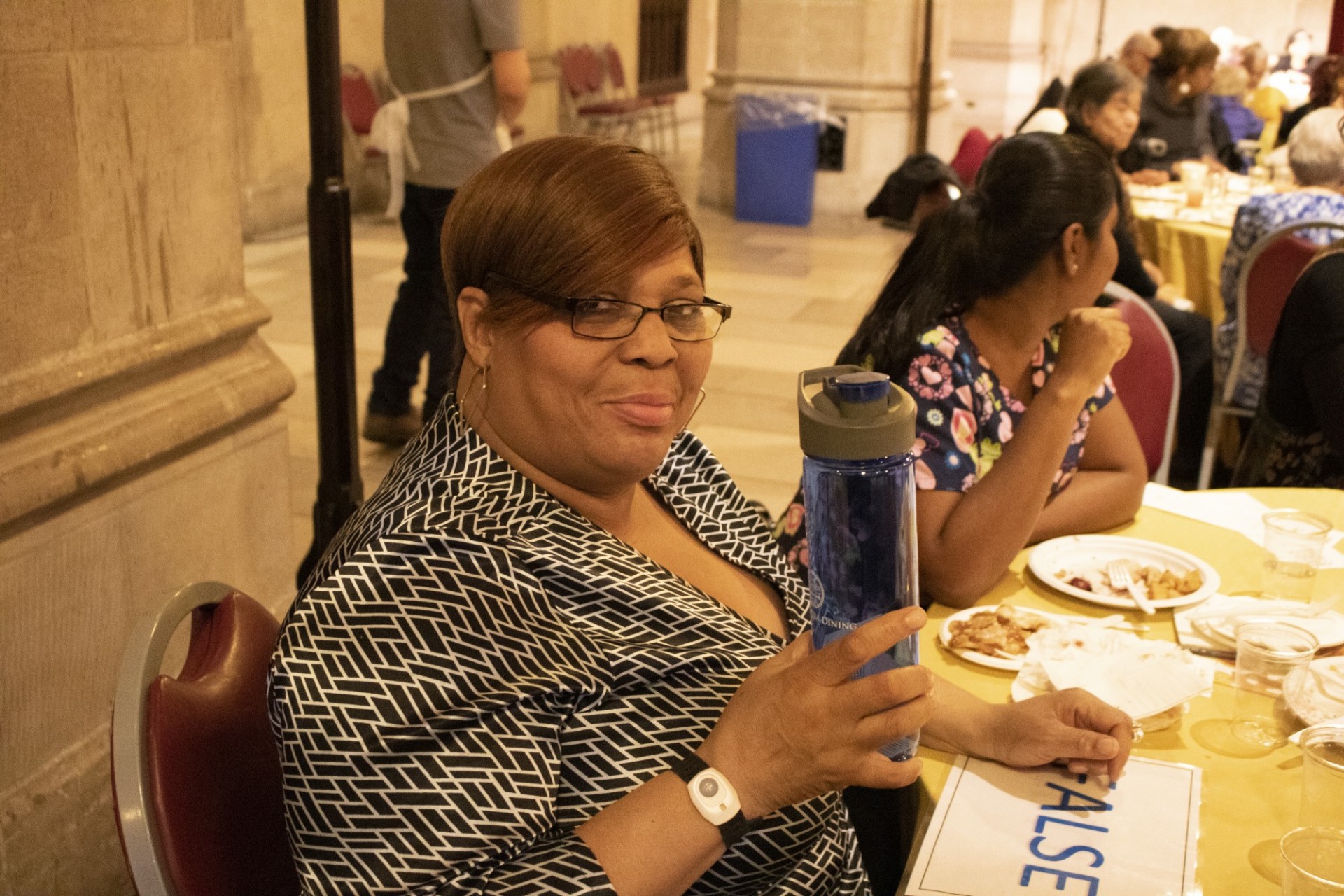 A woman holding up a Columbia Dining water bottle