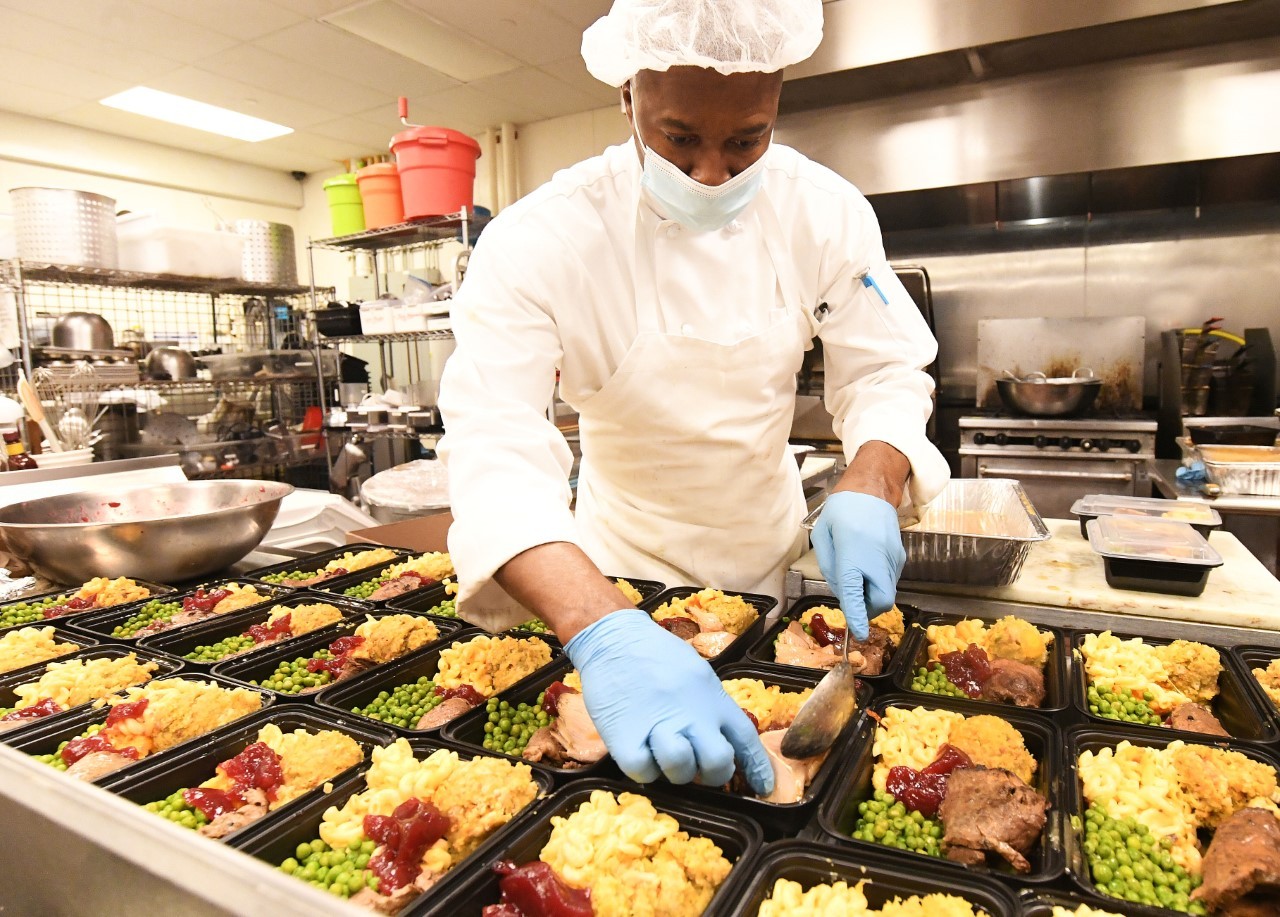 Chef Cornel of Cornel’s Catering Company at Hot Bread Kitchen in East Harlem preparing 150 pre-Thanksgiving meals for local senior citizens. Photo Credit: Eileen Barroso Chef preparing food with face mask on.