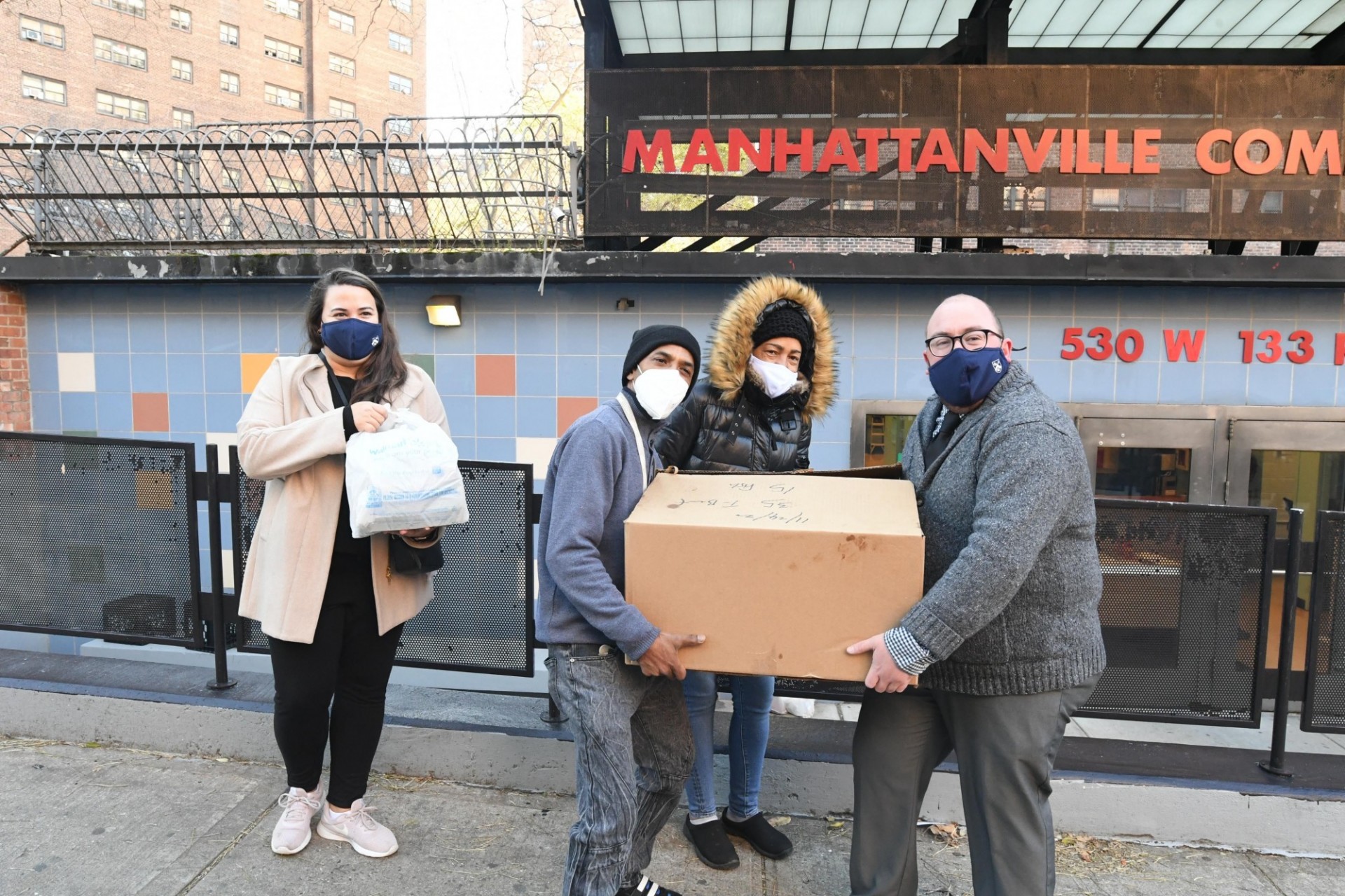 One woman with a face mask carrying bag with food and three (two men and one woman) with a face mask carrying box with meals.