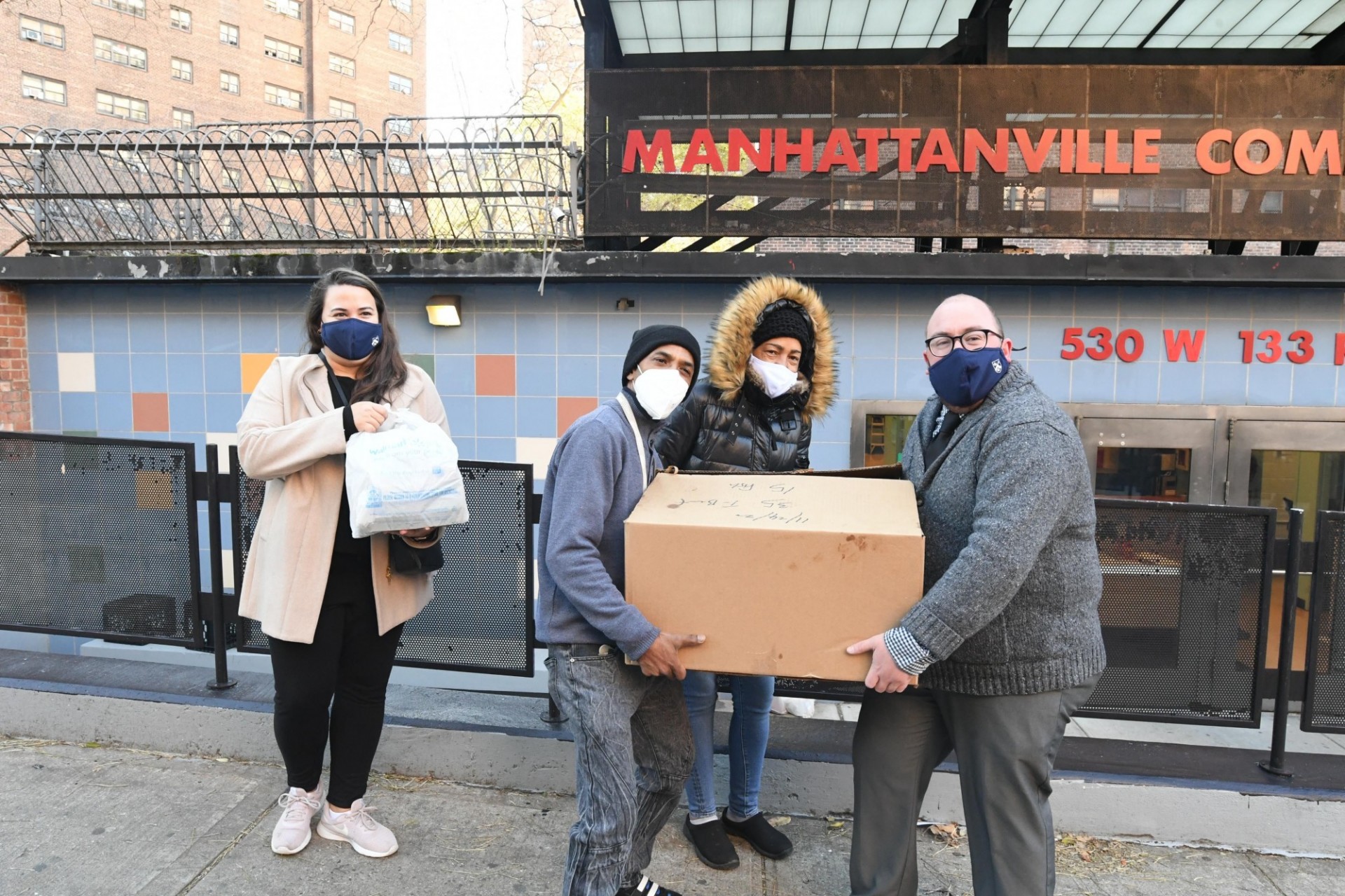 Facilities and Operations staff members safely deliver pre-Thanksgiving meals to local senior citizens. Photo Credit: Eileen Barroso One woman with a face mask carrying bag with food and three (two men and one woman) with a face mask carrying box with meals.