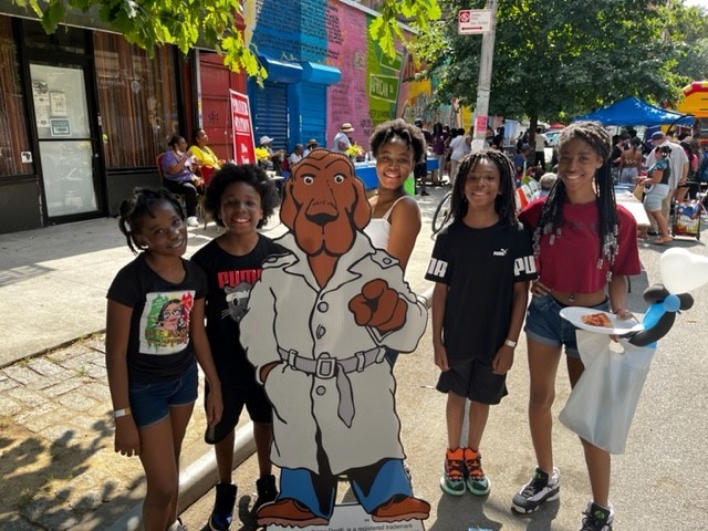 five female students posing with Public Safety's cut-out crime dog in Harlem