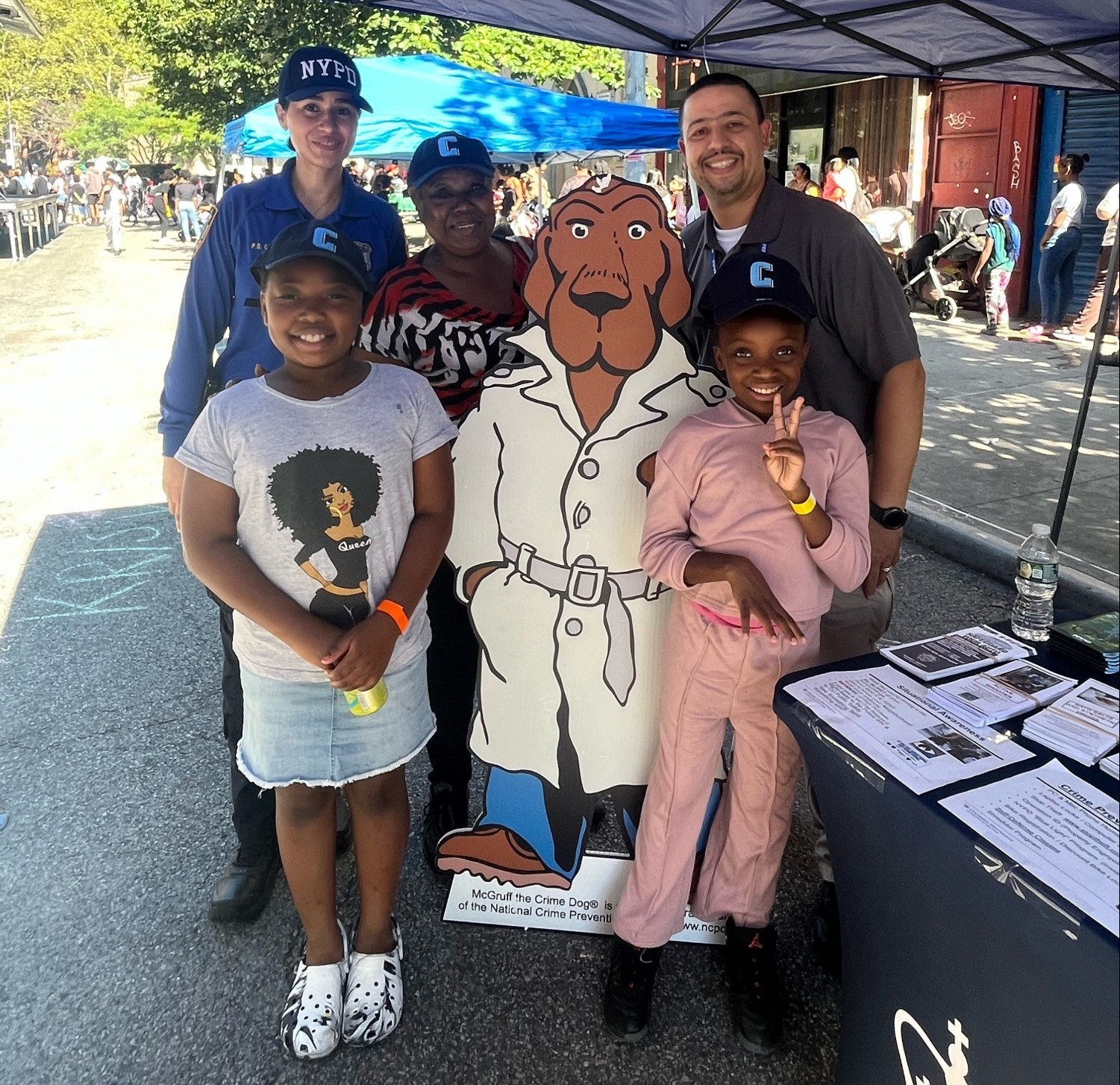 NYPD officer and Public Safety officer pose for a photo with two children and a woman at the annual back to school event