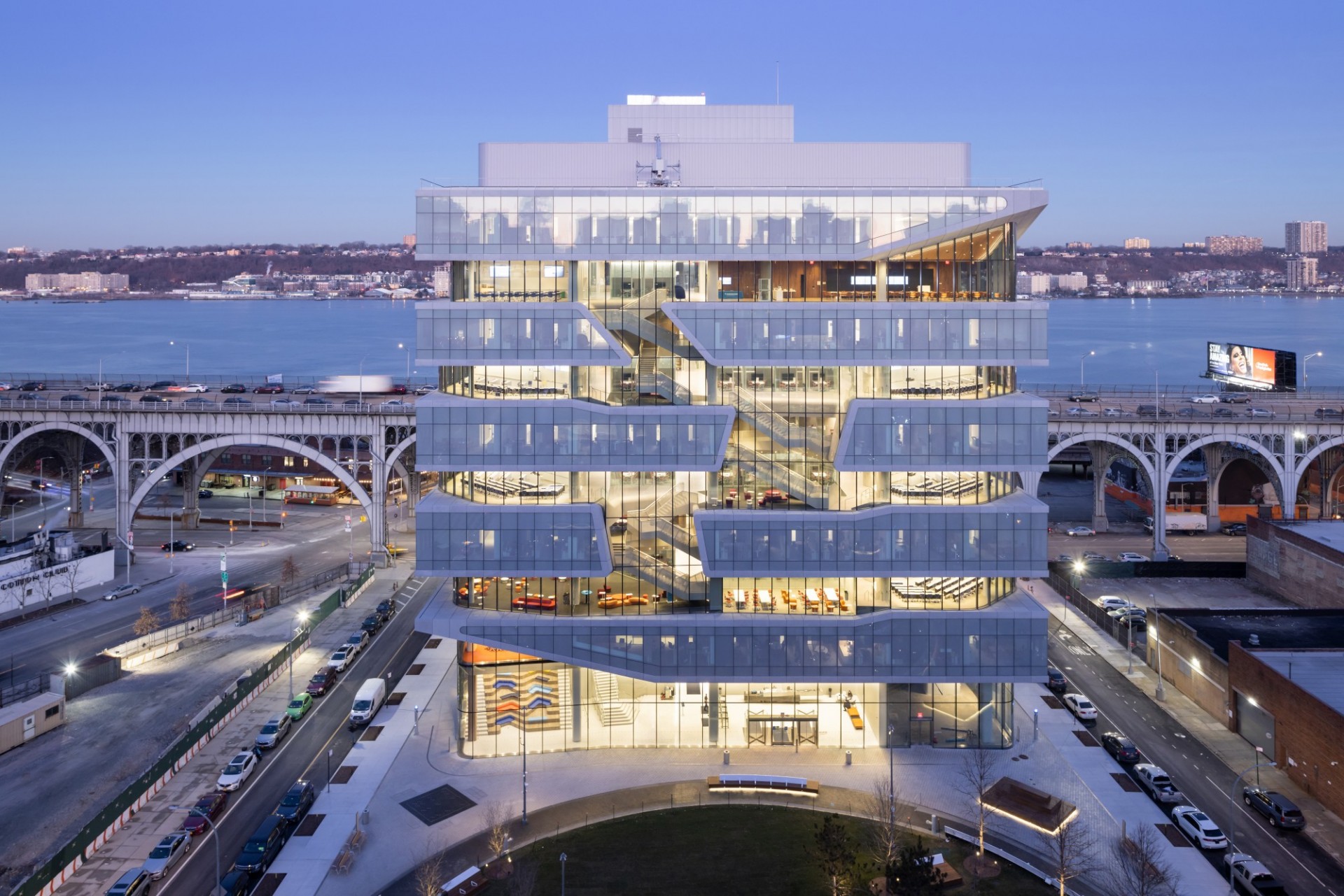 A view of Henry R. Kravis Hall during dusk, with the Viaduct and Hudson River in the background.