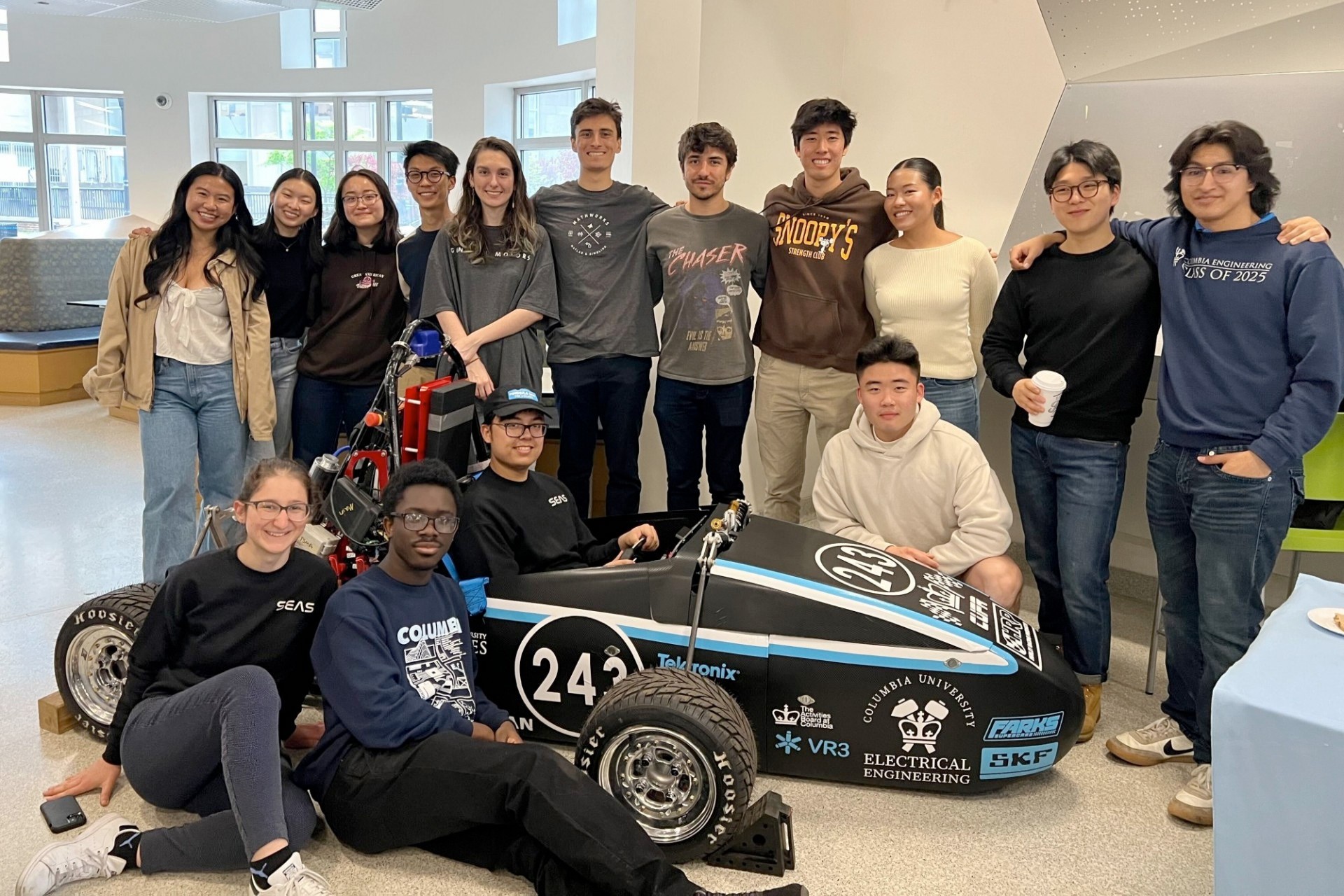 A group of Columbia Formula SAE Racing team members gather round an electric Formula 1 car they fabricated.