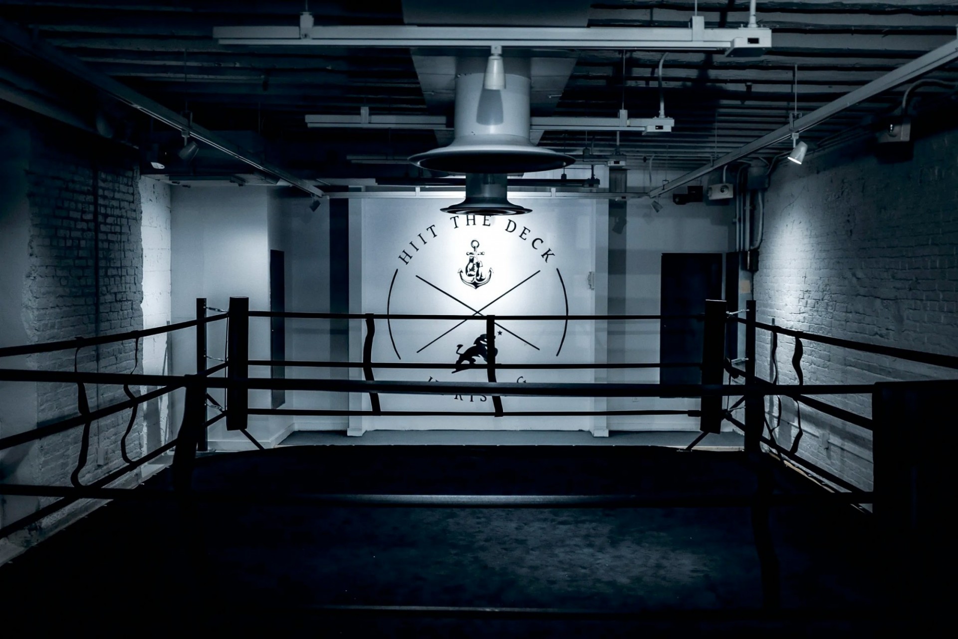 The interior of a boxing gym that is very dim, with a HIIT the Deck logo on the wall.