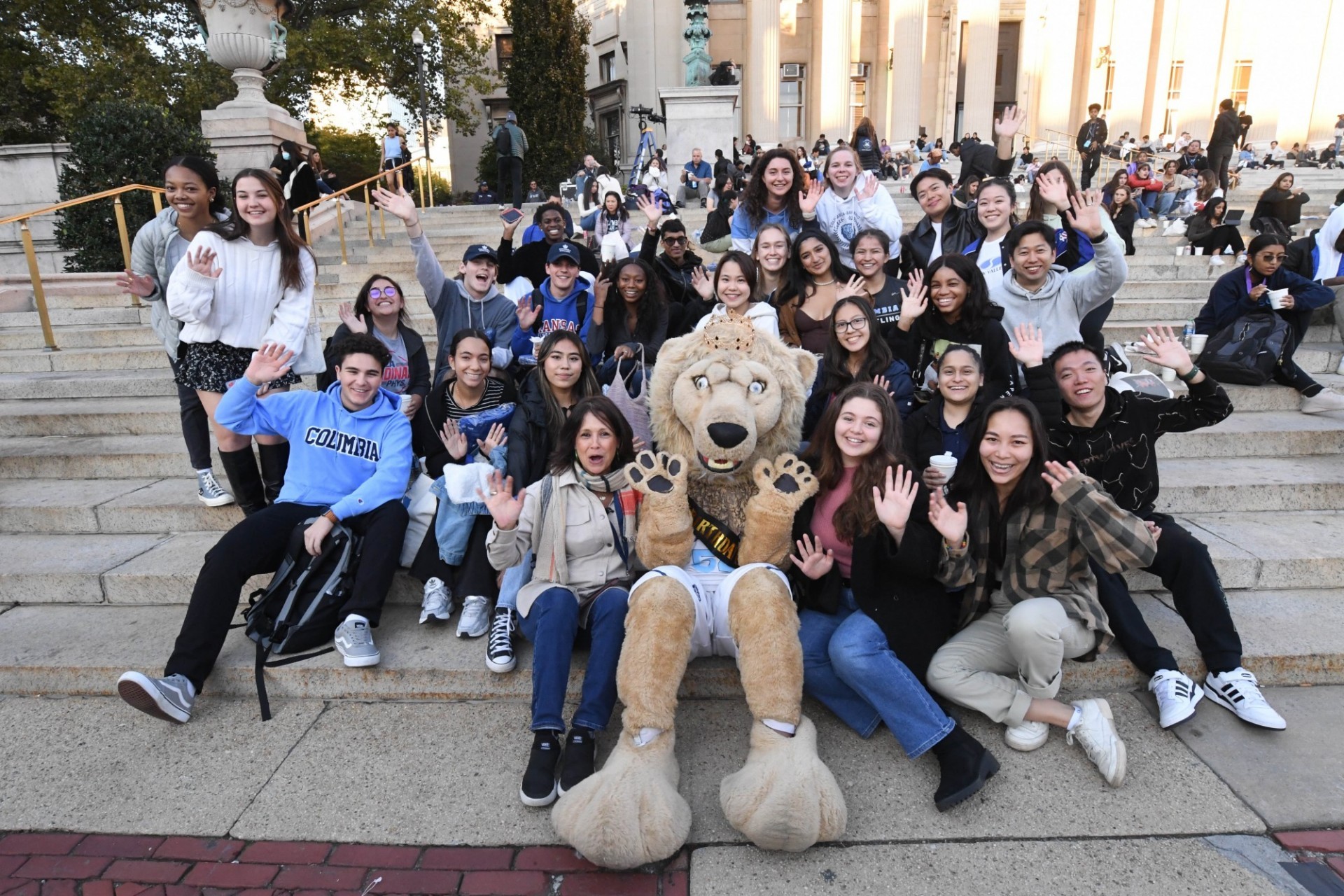Students, family and alumni sit on the Low steps with Roaree