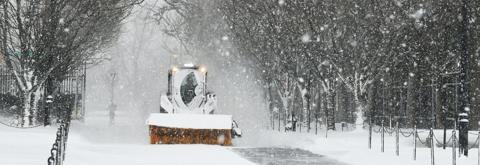 A snowplow clears a path across a snowy College Walk.